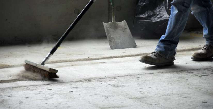 Ein Man fegt den Bauschutt mit einem Besen