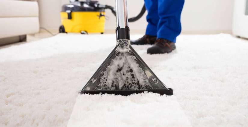Ein Man reinigt ein Teppich mit einem Teppichreinigungsmaschiene.